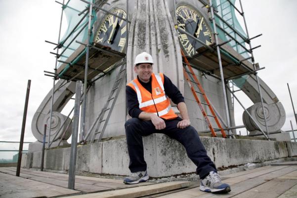 a builder in safety clothing at the top of a church tower
