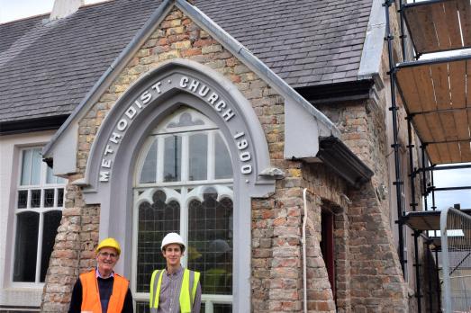 Two people with his-vis jackets standing in front of a church