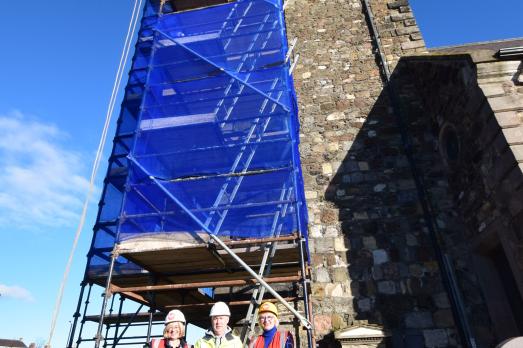 A group of people in hard hats and his-vis jackets stand outside of a church in Northern Ireland