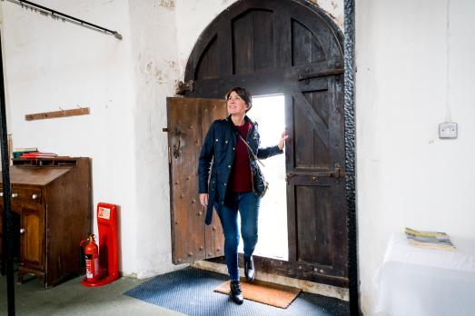 A woman enters a church, looking around it in wonder