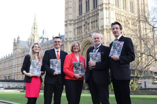 A group of people standing outside the Houses of Parliament