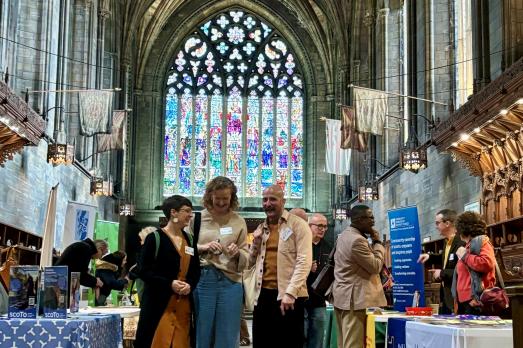 Three people chatting as they walk towards the camera inside Paisley Abbey