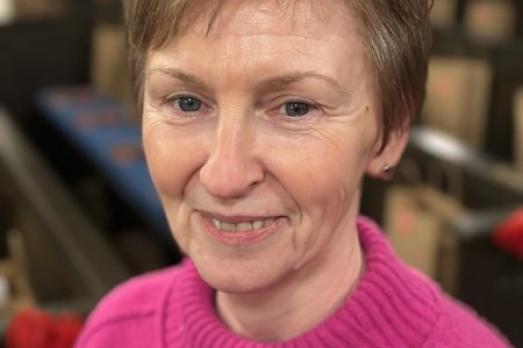 A close up image of a woman wearing a pink jumper