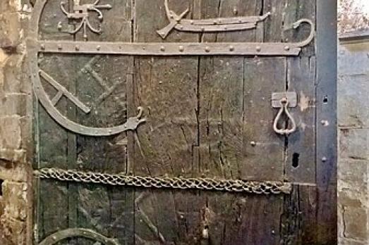 A very old wooden door with iron decorative features