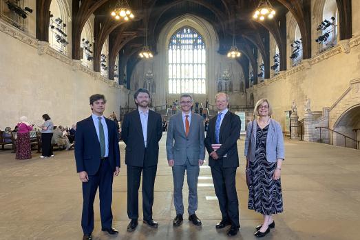 The National Churches Trust Public Affairs and Policy Team with our Chair, Sir Philip Rutnam, and Chief Executive Claire Walker inside Westminster Hall. A large arched window is behind the team.