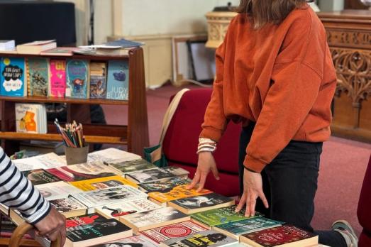 A woman stands behind a trestle table with books on it