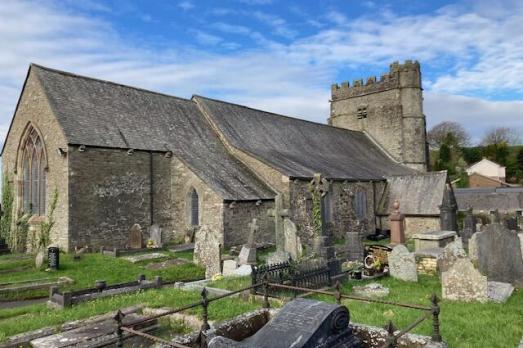 A grey church in a grassy churchyard