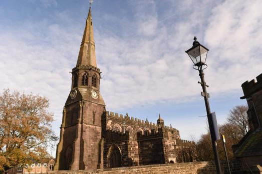A church with a pointed spire next to a lampost