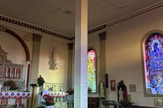The interior of St Francis Hill Chapel. You can see rows of wooden pews facing an ornate altar