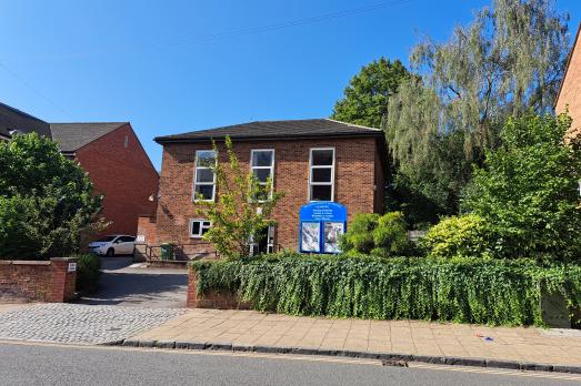 A red brick meeting house surrounded by trees