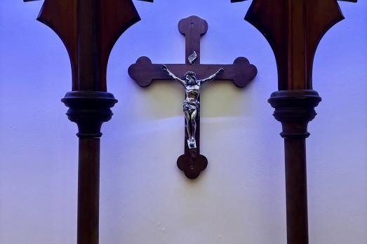 A wooden cross with a silver sculpture of Jesus Christ. This is hanging on the wall of the cathedral.