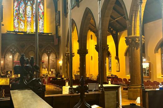 Rows of wooden pews are visible, as well as archways and a stained glass window at the back. This is part of the interior of Inverness Cathedral.