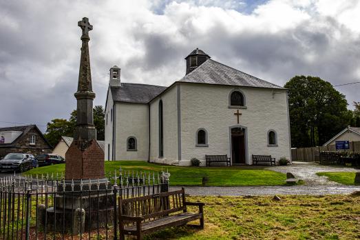The white exterior of Killin & Ardeonaig Pairsh Church in Perthshire with a memorial to the front of the photo