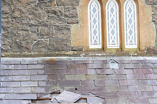 A church with many slipped tiles on its roofs following storm damage