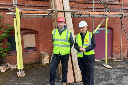 Two workers next to scaffolding outside a church