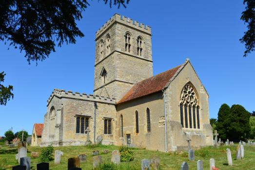A beautiful stone church photographed on a bright sunny day. The tower is prominent the middle of shot.