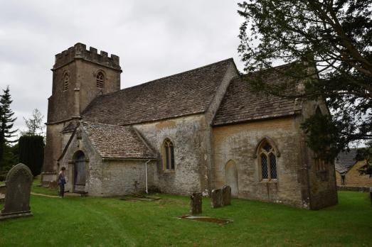A large stone church with a porch to the front and a square tower on the left-hand side of the image. The church has been shot on a grey day.