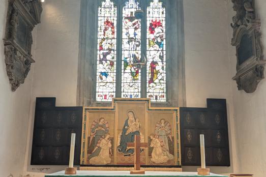 The altar with a stained glass window behind it