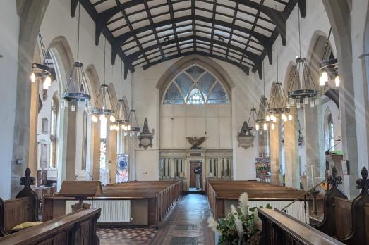 Beautiful interior of St Mary; rows of pews and and a beamed ceiling is visible