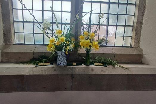 Tow vases of daffodils on the church windowsill 