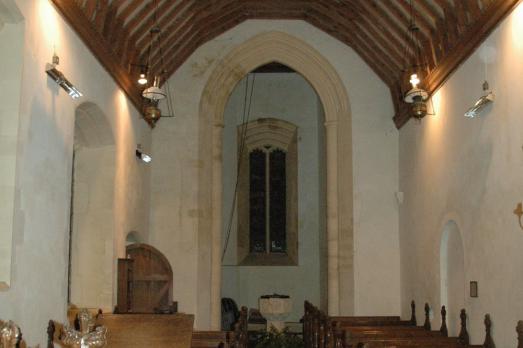 Interior of St Margaret; a beamed ceiling and rows of wooden pews.
