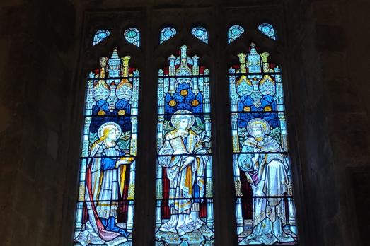 A three-light stained glass window with lots of blue.