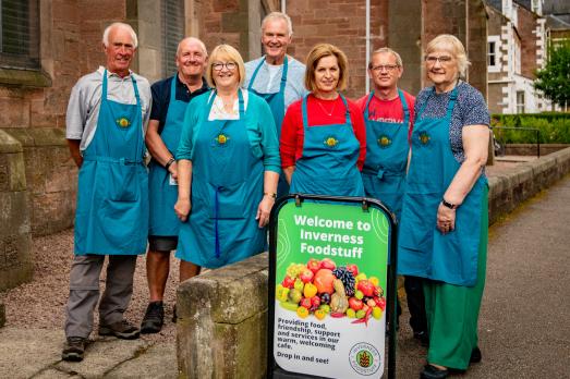 A group of volunteers wearing aprons stand outside a church