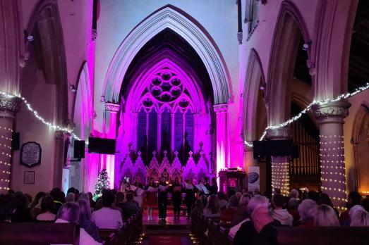 A dimmed church with lots of people sat facing the alter