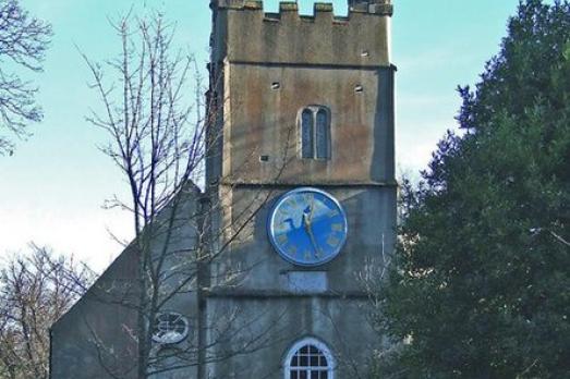 The stone exterior of Stoke Damerel Church with an England flag flying from the tower