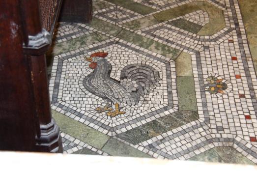 A tiled and patterned floor with a chicken at the centre of the pattern
