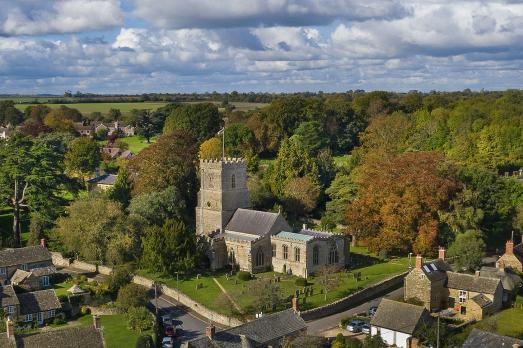A drone photo of St Peter & St Paul; there is much lush greenery around the church
