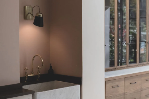 The image shows a kitchen area with a small white sink and a cabinet next to it, made of glass and wood.