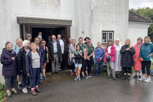 A group of people stand outside a white church