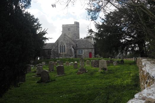 A stone church photographed from a distance with trees surrounding it