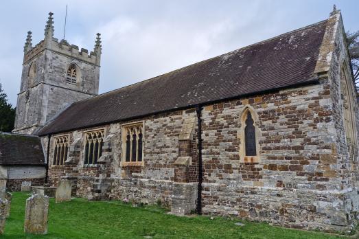 A long grey stone church with a tower to the left of the image