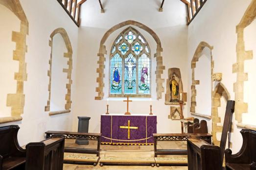 The chancel inside St Nicholas of Myra. It has been recently restored, so looks pristine. There is a large stained glass window behind the altar.