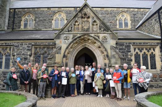 A smiling group of people outside a church building ready for a church tour