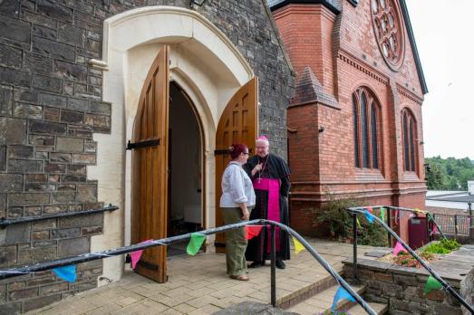 Two people stand outside a church with open doors