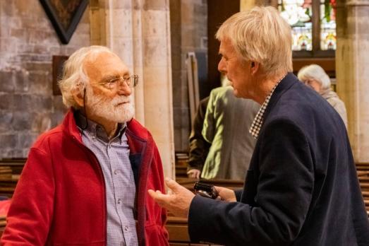 Two men inside a church have a conversation