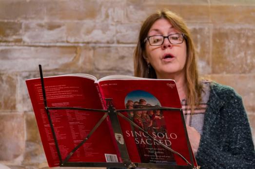 A woman standing behind a music stand, singing