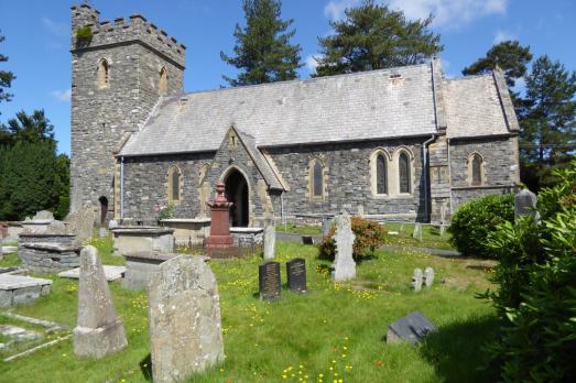 A grey stone church with a tower on the left-hand side. Photographed on a sunny day.