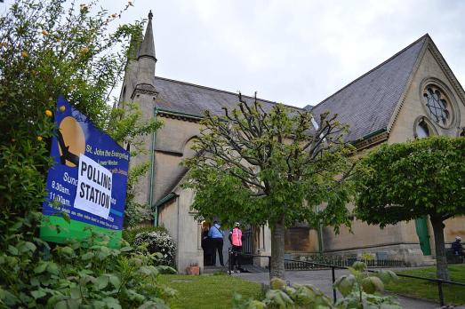 A church surrounded by trees and a sign saying 'polling station'
