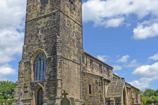 Photograph of the front of St Peter stone church with its prominent tower at the entrance of the building 