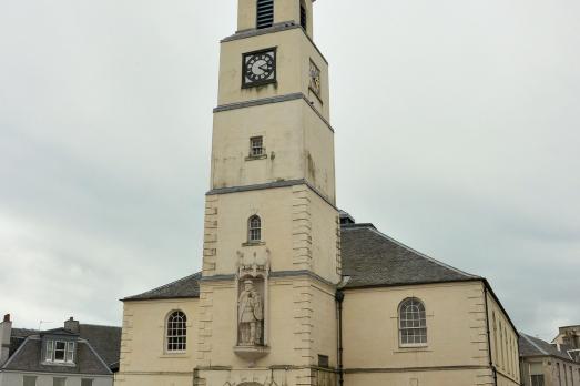 Exterior shot of a pale-coloured brick church with a tower.
