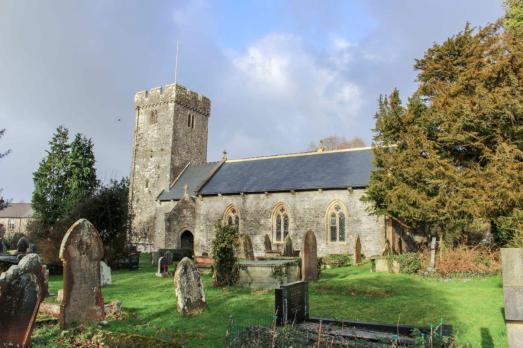 A grey-stone church with a prominent tower on the left-hand side. 