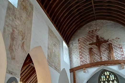 Wall painting adorn the left hand side of the image with a cross above the altar