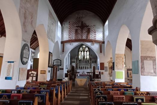 The interior of St Illtud; rows of pews face an altar with archways either side