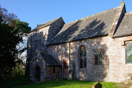 A stone church with shadows of a tree on its front
