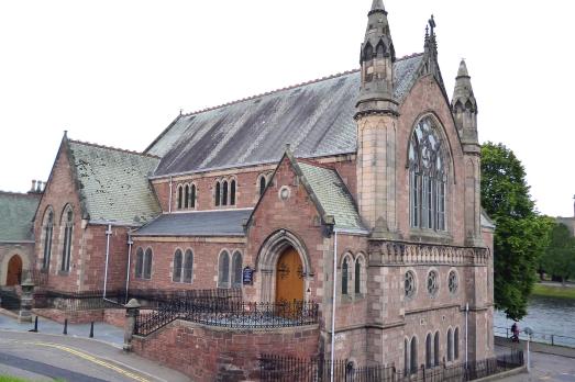 A large impressive red brick church with a ramp leading up to the door