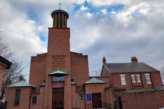 A striking modern church building with a central tower and spire